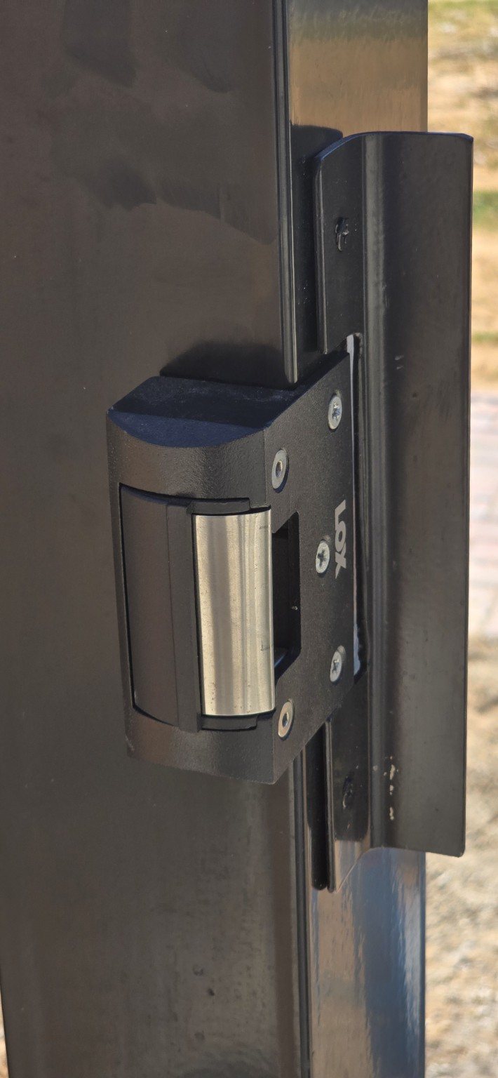 Electric strike installed to secure a black metal gate
