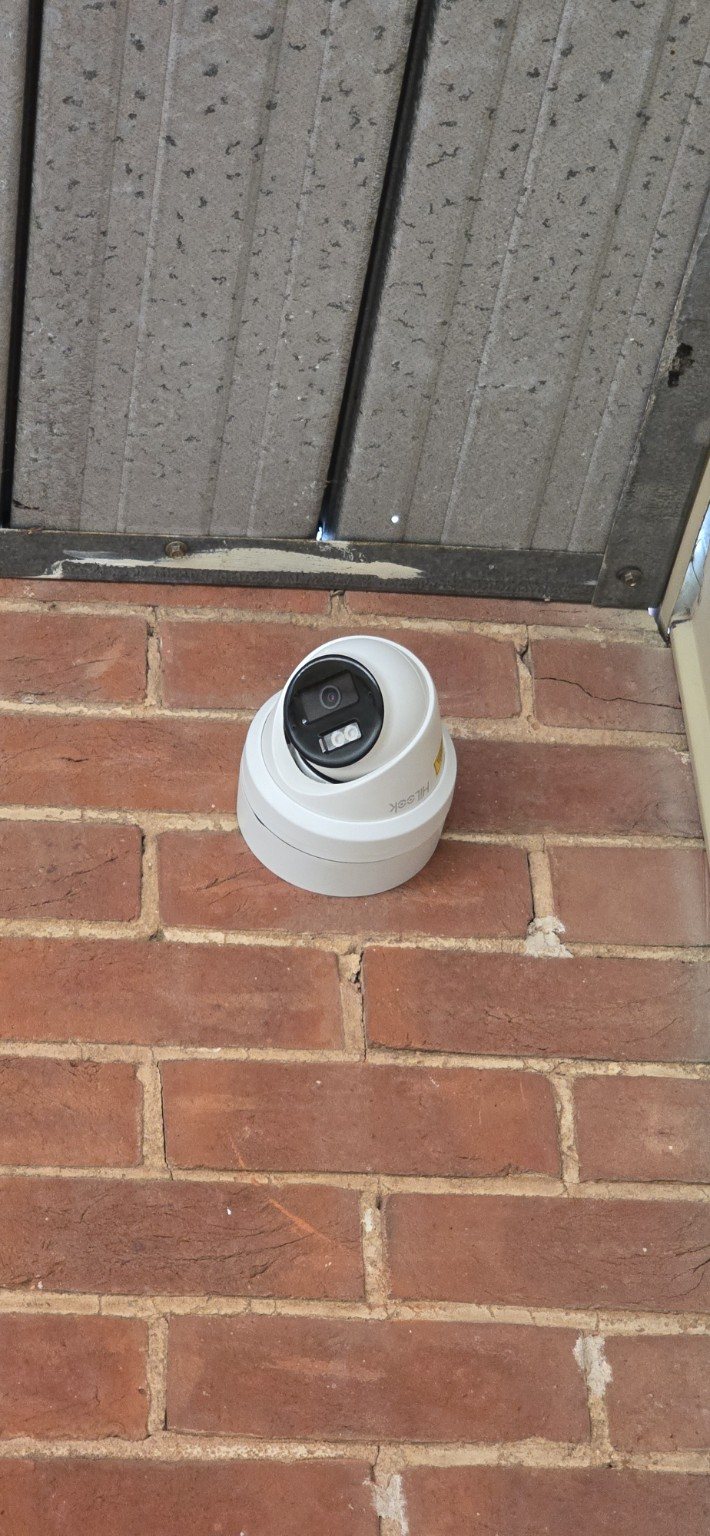 Security camera installed high on a brick wall under an eave